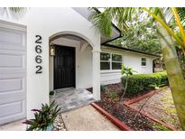 Inviting front entrance with a black door, decorative light, and tiled walkway at 2662 Oakbrook Dr, Largo, FL 33770
