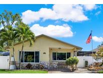 Charming home features a light yellow exterior, stone accents, palm trees, and an American flag at 3060 55Th N Ave, St Petersburg, FL 33714
