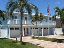 Charming two-story coastal home featuring a spacious balcony, palm trees, and a manicured front yard at 324 6Th Ave, Indian Rocks Beach, FL 33785