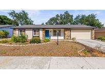 Charming single-story home with stone accents, a manicured lawn and a bright blue front door at 4018 Highgate Dr, Valrico, FL 33594