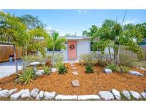 Charming home featuring a landscaped front yard, stone pathway, and a welcoming coral-colored front door with wreath at 5365 Flamingo Dr, St Petersburg, FL 33714