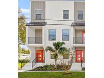 Modern townhome showcases clean lines, black framed windows, balcony, and vibrant red doors at 6904 S Macdill Ave # 1, Tampa, FL 33611