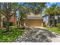 Charming two-story home with a tan exterior, attached garage, mature trees, and landscaped front yard at 7023 Montauk Point Xing, Bradenton, FL 34212