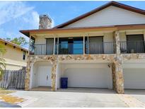 Two-story home with stone accents, upper balcony, and a three-car garage at 7085 Sunset S Dr # A, St Petersburg, FL 33707