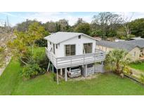 Charming two-story home with a deck and a well-maintained lawn and space for a car underneath the house at 9706 N 22Nd St, Tampa, FL 33612