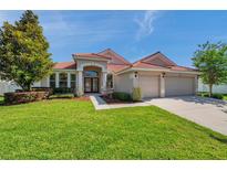 Charming single-story home featuring a red tile roof, manicured lawn, and a welcoming double-door entrance at 2218 Valterra Vista Way, Valrico, FL 33594
