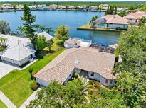 Stunning aerial view of waterfront home with tile roof, screened pool, private dock, and lush landscaping at 5818 Cruiser Way, Tampa, FL 33615