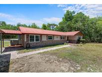 Front exterior view featuring red roof, brick accents, and walkway at 7095 South St, Webster, FL 33597