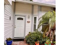 Charming home featuring a decorative front door, lush landscaping, and a vibrant palm tree at 840 Franklin Cir, Palm Harbor, FL 34683
