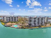 Stunning aerial view of the Constellation building with pool, lush landscaping, and boat docks on shimmering blue water at 9425 Blind Pass Rd # 802, St Pete Beach, FL 33706