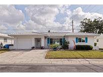 Charming single-story home featuring white tile roof, blue shutters, manicured lawn and attached garage at 9511 45Th N St # 9511, Pinellas Park, FL 33782