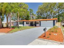Charming single-story home with a well-maintained lawn and a distinctive orange tile roof and a grey driveway at 2156 Greenbriar Blvd, Clearwater, FL 33763