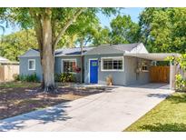 Charming single-story home with a blue front door, mature trees, carport, and a well-maintained front yard at 3005 W Helen Ave, Tampa, FL 33611