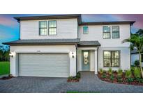 Charming two-story home with white siding, a gray roof, an attached garage, and landscaped yard at 5953 Bluestar Ct, Lakewood Ranch, FL 34211