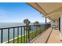 Relax on the tiled balcony with metal railings and a seating area, overlooking the lush lawn and ocean view at 7540 Sunshine Skyway S Ln # 219, St Petersburg, FL 33711