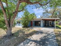 Charming single-story home with covered parking, mature trees, and a vibrant red front door at 8014 N Lynn Ave, Tampa, FL 33604