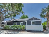 Charming home featuring dark siding, a white accent wall, and mature trees in a landscaped front yard at 847 Highland N St, St Petersburg, FL 33701
