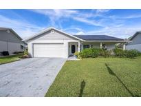 Charming single-story home featuring a two-car garage, solar panels, and well-maintained lawn at 9413 Stonewall Ln, New Port Richey, FL 34655
