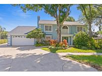 Inviting two-story home featuring lush landscaping, a two-car garage, and charming architectural details at 13548 Lake Magdalene Dr, Tampa, FL 33613