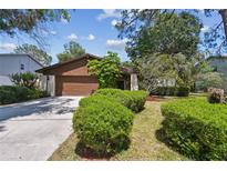 Charming home featuring a brown exterior, well-kept landscaping, and a two-car garage at 16503 W Course Dr, Tampa, FL 33624