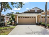 Home's two-car garage with decorative windows, manicured lawn, and walkway to front door at 19129 Lake Audubon Dr, Tampa, FL 33647