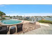 Inviting pool with waterfront views, dock, brick patio with wicker furniture, and serene landscape at 2511 Bay Blvd # B, Indian Rocks Beach, FL 33785