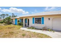Charming single-story home with bright blue shutters, lush greenery, and well-maintained lawn at 2810 9Th St, Englewood, FL 34224