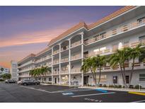 Multi-story condo building with white facade, open balconies, parking and guest spaces, and mature palm tree landscaping at 3128 59Th S St # 206, Gulfport, FL 33707