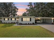 Charming single-story home featuring a carport, well-maintained lawn, and mature trees under a beautiful evening sky at 403 Westbrook Ave, Brandon, FL 33511