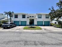 Symmetrical townhome exterior featuring colorful trim, blue garage doors and shared green space at 6534 Fairway Gardens Dr # 17-201, Bradenton, FL 34203