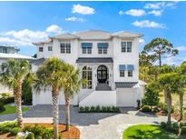 Elegant two-story home featuring a white exterior, gray roof, blue awnings, and professionally landscaped front yard at 885 Seaview Cir # 20, Crystal Beach, FL 34681