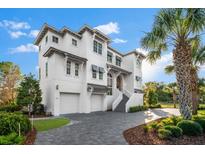 Stunning three-story white home featuring a two-car garage, elegant stairway, and lush landscaping at 885 Seaview Cir # 20, Crystal Beach, FL 34681