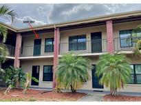 Two-story building featuring brick and tan exterior, black railings, and tropical landscaping in front at 1020 85Th N Ave # 222, St Petersburg, FL 33702