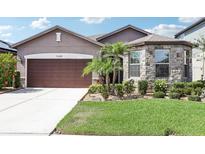 Charming single Gathering home featuring a stone facade accent and a well-maintained lawn with palms at 11688 Brighton Knoll Loop, Riverview, FL 33579