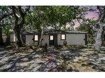 Charming single-story home with mature trees and a welcoming entrance with a gray door at 1247 21St St, Sarasota, FL 34234