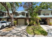 Charming townhome featuring a brick facade, green metal roof, garage and walkway to the front door at 1486 Mahogany Ln # 703, Palm Harbor, FL 34683