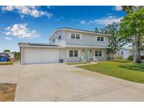Inviting two-story home with a well-manicured lawn, charming front porch, and a spacious driveway leading to an attached garage at 1501 84Th N Ave, St Petersburg, FL 33702