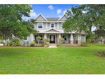 Charming two-story home boasts a welcoming front porch and well-manicured lawn, nestled amongst mature trees at 18929 Crescent Rd, Odessa, FL 33556