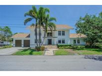 A two-story home with a white exterior, a brown roof and two palm trees in the front yard at 2114 S Venus St, Tampa, FL 33629