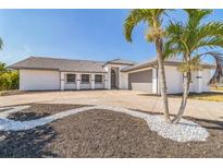 Beautiful single-story home featuring tropical landscaping, a spacious driveway, and an attached two-car garage at 2161 Aqui Esta Dr, Punta Gorda, FL 33950