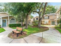 Charming exterior view of tan townhomes with mature trees, lush landscaping, and inviting walkways at 2373 Hounds Trl, Palm Harbor, FL 34683