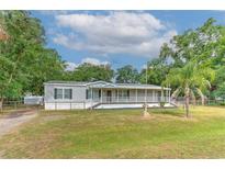 Charming single-story home with a spacious front porch, surrounded by mature trees and lush green lawn at 6633 Applewood Dr, Wesley Chapel, FL 33544