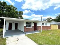 Charming single-story home featuring a carport, brick accents, and a well-maintained front lawn at 8310 Croton Ave, Tampa, FL 33619