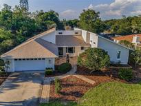 Beautifully landscaped home with a well-maintained lawn, brick walkway, and attached two-car garage at 833 Lakeside Ter, Palm Harbor, FL 34683