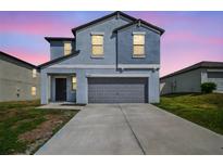 Two-story home boasts a modern design, two-car garage, and well-manicured lawn in a suburban neighborhood at 10013 Caraway Spice Ave, Riverview, FL 33578