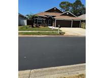 Charming single-story home featuring a three-car garage and a well-maintained front yard at 1747 Wood Brook St, Tarpon Springs, FL 34689