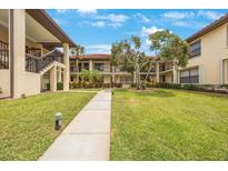 Beautifully landscaped courtyard with mature trees, lush green grass, and sidewalk leading to two-story building at 404 Hammock Pine Blvd # 404, Clearwater, FL 33761