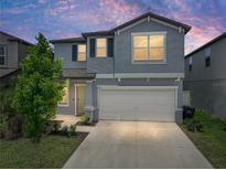 Two-story home featuring light blue siding, a gray roof, attached two car garage, and a well-maintained lawn at dusk at 413 Royal Empress Dr, Ruskin, FL 33570