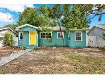 Charming turquoise home featuring a bright yellow front door, white window frames, and young palm trees at 4330 7Th N Ave, St Petersburg, FL 33713