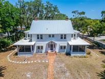 Charming two-story home with wraparound porch, lush trees, and brick path at 5603 Palmetto Rd, New Port Richey, FL 34652